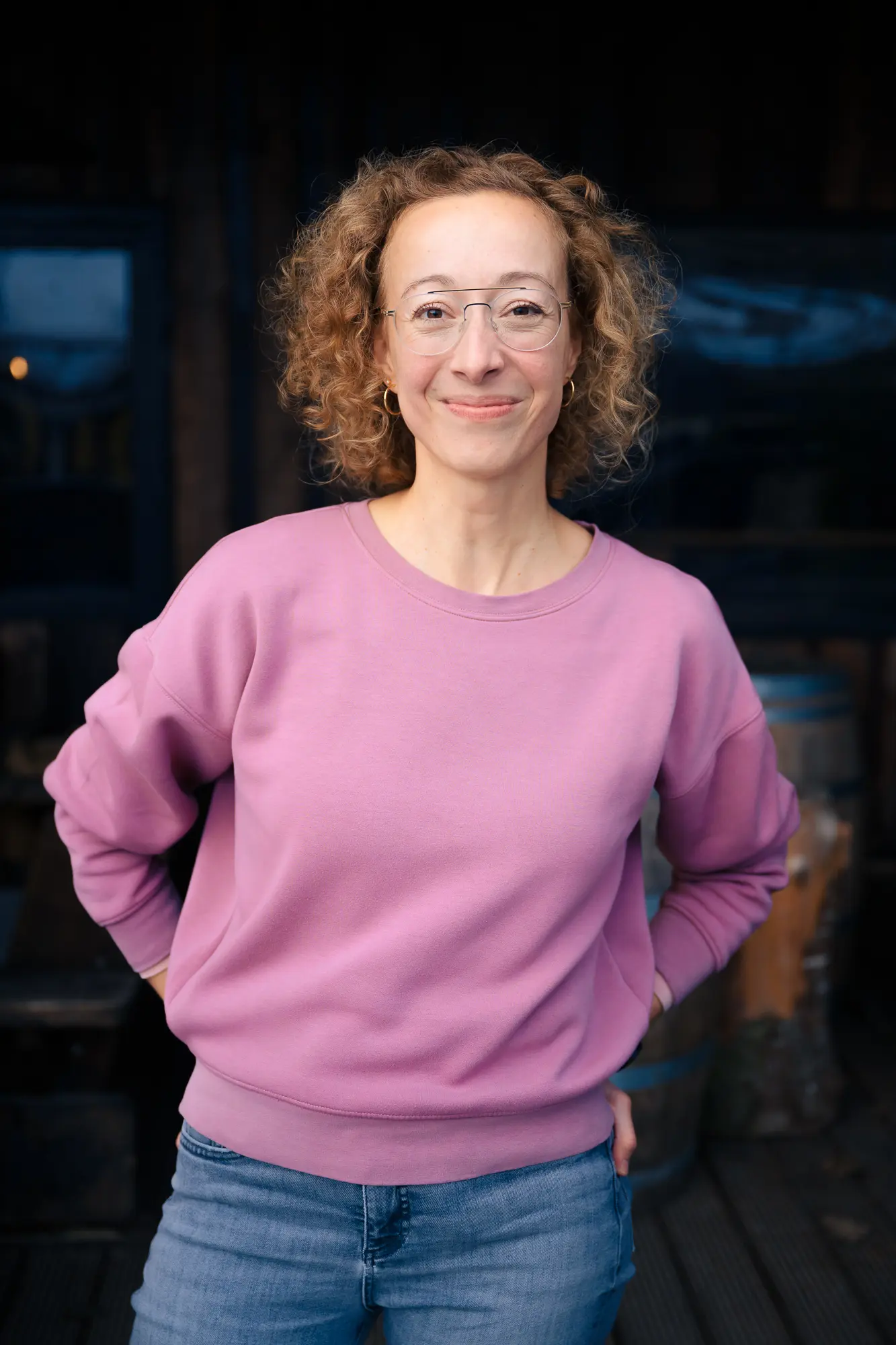 Portrait von Heike Stier, Psychologische Beraterin, im fliederfarbenen Pullover mit Händen auf die Hüften gestützt